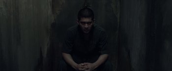 Movie still from “The Raid 2” (2014), directed by Gareth Evans – A man sitting in front of a wooden wall; Medium shot, Low angle