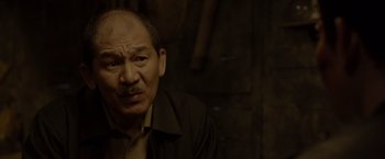 Movie still from “The Raid 2” (2014), directed by Gareth Evans – An older man in a brown jacket looking at the camera; Close Up shot, Over the shoulder angle