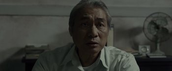 Movie still from “The Raid 2” (2014), directed by Gareth Evans – An older man in a white dress shirt looking at the camera; Close Up shot, Low angle