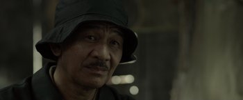 Movie still from “The Raid 2” (2014), directed by Gareth Evans – A person wearing a hat; Close Up shot, Over the shoulder angle