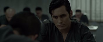 Movie still from “The Raid 2” (2014), directed by Gareth Evans – A person sitting in front of a group of people; Close Up shot, Over the shoulder angle