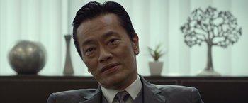 Movie still from “The Raid 2” (2014), directed by Gareth Evans – A person wearing a suit and tie; Close Up shot, Low angle