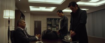 Movie still from “The Raid 2” (2014), directed by Gareth Evans – A man standing next to another man with a bag; Medium shot, Over the shoulder angle