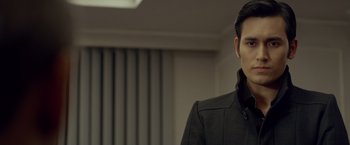 Movie still from “The Raid 2” (2014), directed by Gareth Evans – A man wearing a black jacket standing in a room; Close Up shot, Over the shoulder angle