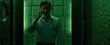 Movie still from “The Raid 2” (2014), directed by Gareth Evans – A man is talking on a cell phone in front of a wall; Medium shot, Low angle