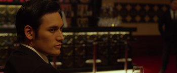 Movie still from “The Raid 2” (2014), directed by Gareth Evans – A young man is standing in front of a bar; Close Up shot, Over the shoulder angle