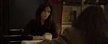 Movie still from “The Raid 2” (2014), directed by Gareth Evans – A woman sitting at a table with a glass of wine in front of her; Close Up shot, Over the shoulder angle