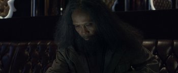 Movie still from “The Raid 2” (2014), directed by Gareth Evans – A man with long black hair and a long beard; Close Up shot, Over the shoulder angle
