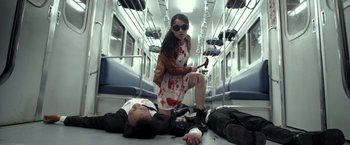 Movie still from “The Raid 2” (2014), directed by Gareth Evans – A woman is holding a knife in front of a man on the floor; Medium shot, Low angle