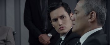 Movie still from “The Raid 2” (2014), directed by Gareth Evans – A man wearing a suit and tie looking at the camera; Close Up shot, Over the shoulder angle