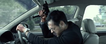 Movie still from “The Raid 2” (2014), directed by Gareth Evans – A man in a car holding a gun up to his head; Close Up shot, High angle