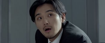 Movie still from “The Raid 2” (2014), directed by Gareth Evans – A person wearing a suit and tie; Close Up shot, Over the shoulder angle