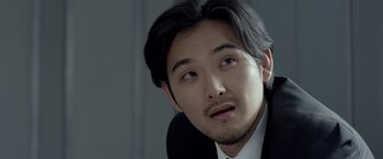 Movie still from “The Raid 2” (2014), directed by Gareth Evans – A person wearing a suit and tie; Close Up shot, Over the shoulder angle