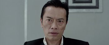 Movie still from “The Raid 2” (2014), directed by Gareth Evans – A person wearing a suit and tie; Close Up shot, Low angle