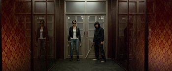 Movie still from “The Raid 2” (2014), directed by Gareth Evans – A man and a woman standing next to each other in front of a door; Wide shot, Low angle