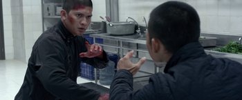 Movie still from “The Raid 2” (2014), directed by Gareth Evans – Two men in a kitchen one with blood on his face and the other with blood on his hand; Medium shot, Over the shoulder angle