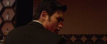 Movie still from “The Raid 2” (2014), directed by Gareth Evans – A person wearing a suit and tie; Close Up shot, Low angle