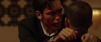 Movie still from “The Raid 2” (2014), directed by Gareth Evans – A young man with a bloody face paint touching another man's face; Close Up shot, Over the shoulder angle