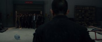 Movie still from “The Raid 2” (2014), directed by Gareth Evans – A group of people standing in front of a building; Wide shot, Over the shoulder angle