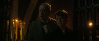 Movie still from “The Sandman” (2022), created by Neil Gaiman – An older man and a young boy standing next to each other; Close Up shot, Low angle