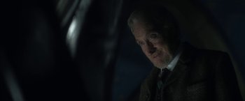Movie still from “The Sandman” (2022), created by Neil Gaiman – An older man in a suit and tie looking at the camera; Close Up shot, Over the shoulder angle