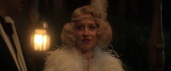 Movie still from “The Sandman” (2022), created by Neil Gaiman – A person wearing a feather boa; Close Up shot, Low angle