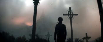 Movie still from “The Sandman” (2022), created by Neil Gaiman – A man standing in front of a cross and a castle; Extreme Wide shot, Over the shoulder angle