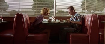 Movie still from “Pulp Fiction” (1994), directed by Quentin Tarantino – A man and a woman sitting at a table in front of a window; Medium shot, Low angle