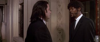 Movie still from “Pulp Fiction” (1994), directed by Quentin Tarantino – A man with long black hair standing next to a woman; Medium shot, Over the shoulder angle