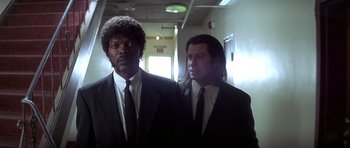 Movie still from “Pulp Fiction” (1994), directed by Quentin Tarantino – Two men in suits and ties standing next to each other; Medium shot, Low angle