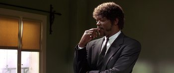 Movie still from “Pulp Fiction” (1994), directed by Quentin Tarantino – A man wearing a suit and tie with his hand to his face; Close Up shot, Low angle