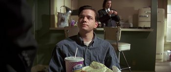 Movie still from “Pulp Fiction” (1994), directed by Quentin Tarantino – A man sitting at a table with a drink in front of him; Close Up shot, Over the shoulder angle