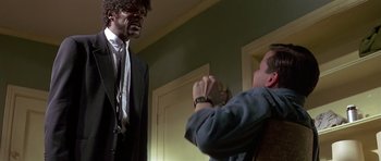 Movie still from “Pulp Fiction” (1994), directed by Quentin Tarantino – A man in a suit and tie is talking to another man in a suit and tie; Medium shot, Over the shoulder angle