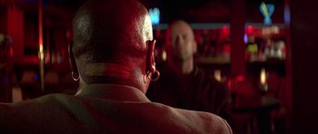 Movie still from “Pulp Fiction” (1994), directed by Quentin Tarantino – A bald man with a beard and a red jacket is looking at himself in the mirror; Close Up shot, Over the shoulder angle