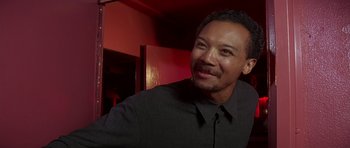 Movie still from “Pulp Fiction” (1994), directed by Quentin Tarantino – A man smiling for the camera while wearing a black shirt; Close Up shot, Low angle