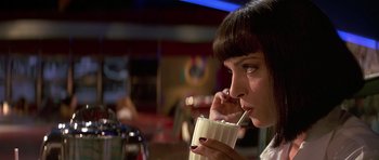 Movie still from “Pulp Fiction” (1994), directed by Quentin Tarantino – A woman is drinking from a cup with a straw; Close Up shot, Over the shoulder angle
