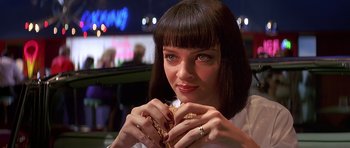 Movie still from “Pulp Fiction” (1994), directed by Quentin Tarantino – A woman is holding a sandwich in her hands; Close Up shot, Over the shoulder angle