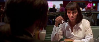 Movie still from “Pulp Fiction” (1994), directed by Quentin Tarantino – A woman sitting at a table in front of a plate of food; Close Up shot, Over the shoulder angle