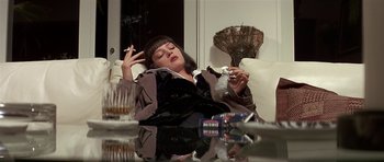 Movie still from “Pulp Fiction” (1994), directed by Quentin Tarantino – A woman sitting at a table smoking a cigarette; Medium shot, High angle