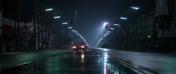 Movie still from “Pulp Fiction” (1994), directed by Quentin Tarantino – A car driving down a wet street at night; Extreme Wide shot, Low angle