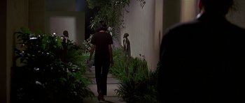 Movie still from “Pulp Fiction” (1994), directed by Quentin Tarantino – A woman walking down a sidewalk near a building; Wide shot, Over the shoulder angle