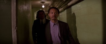 Movie still from “Pulp Fiction” (1994), directed by Quentin Tarantino – A man in a suit and tie standing next to another man in a suit and tie; Medium shot, Low angle