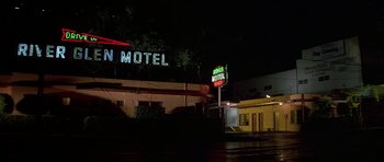 Movie still from “Pulp Fiction” (1994), directed by Quentin Tarantino – A motel sign lit up at night in the dark; Wide shot, Low angle