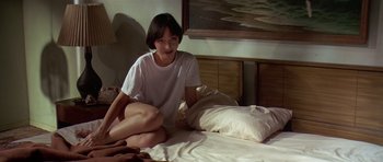 Movie still from “Pulp Fiction” (1994), directed by Quentin Tarantino – A woman sitting on a bed in a room; Medium shot, High angle