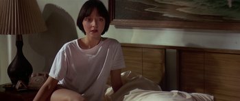 Movie still from “Pulp Fiction” (1994), directed by Quentin Tarantino – A woman sitting on a bed in a room; Medium shot, High angle