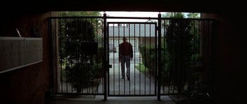 Movie still from “Pulp Fiction” (1994), directed by Quentin Tarantino – A man walking through a gated entrance to a house; Extreme Wide shot, Low angle