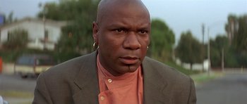 Movie still from “Pulp Fiction” (1994), directed by Quentin Tarantino – A man in a jacket and shirt with a piercing in his ear; Close Up shot, Low angle