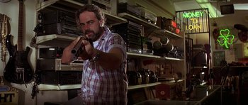 Movie still from “Pulp Fiction” (1994), directed by Quentin Tarantino – A man holding a gun in a room filled with stacks of books; Medium shot, Low angle