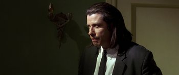 Movie still from “Pulp Fiction” (1994), directed by Quentin Tarantino – A man with long hair wearing a suit and tie; Close Up shot, Over the shoulder angle
