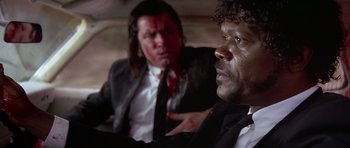 Movie still from “Pulp Fiction” (1994), directed by Quentin Tarantino – Two men in suits and ties sitting next to each other in a car; Close Up shot, Over the shoulder angle